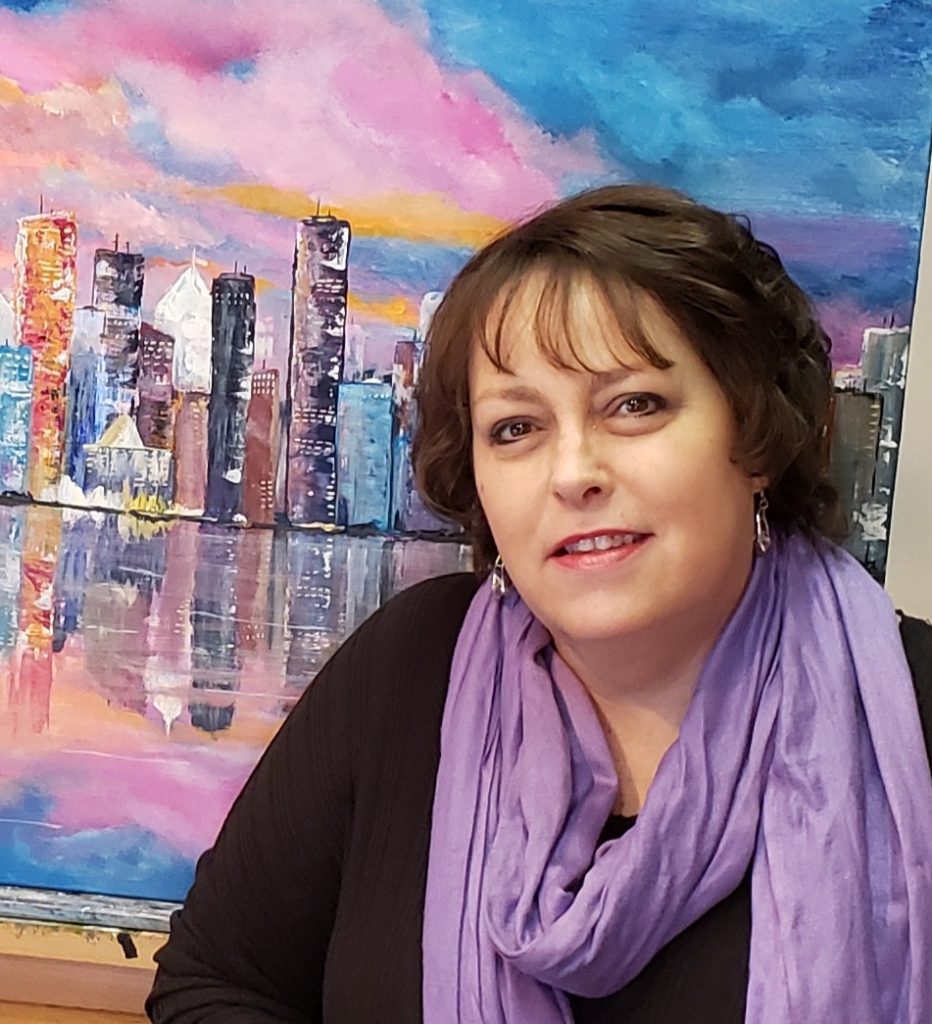 Portrait of Lisa Olson, artist and founder of The Artistic Envelope, smiling in a creative workspace.